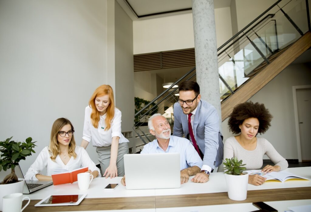 A diverse team in an office setting working happily together to display a high level of emotional intelligence in the modern workplace.